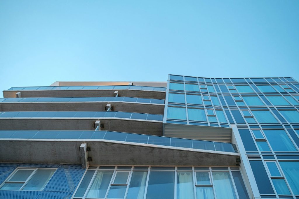 Modernes Gebäude mit blauem Glas und Balkonen vor dem Himmel.